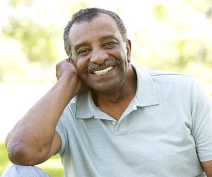 man in a green polo shirt sitting in a park