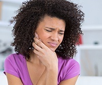 Woman grimacing and holding jaw