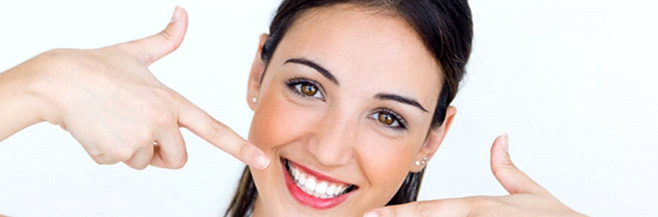 young woman pointing to her smile with veneers in Mount Vernon