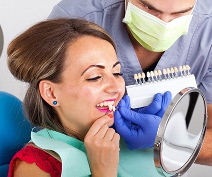 woman holding veneers up to her smile