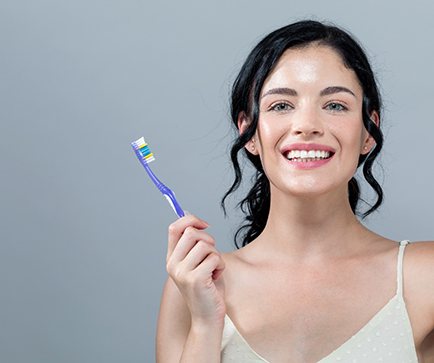 Woman with teeth whitening in Mount Vernon holds toothbrush 