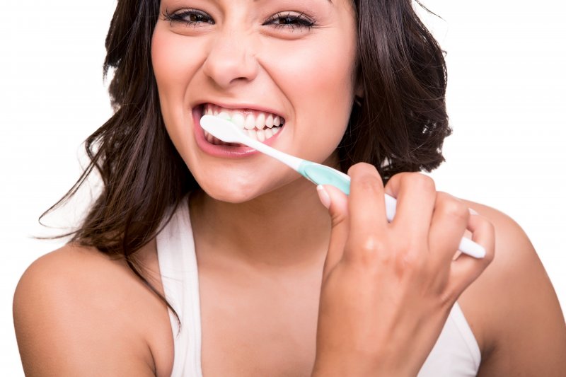 woman brushing her teeth before visiting dentist in Mount Vernon