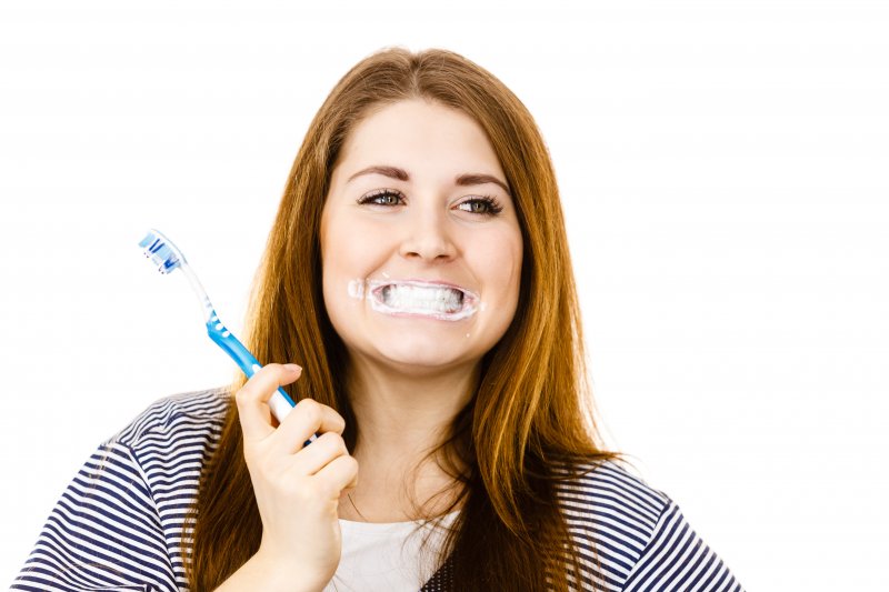 woman cleaning teeth after visiting dentist in Mt. Vernon