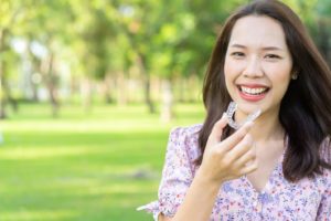 Woman smiling and holding her Invisalign aligner.