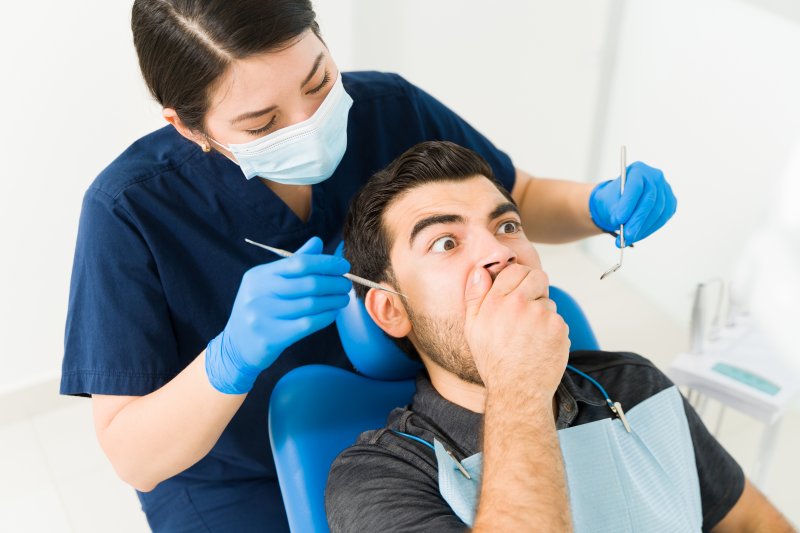 a patient covering his mouth from his dentist